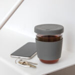 Kaffeebecher Glas, auf dem Bild mit einem Smartphone und einem Schlüsselbund